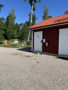Servicehuset på ställplatsen vid Lungers Hamn med röd träfasad och orange tegelpannor