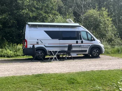Vi njuter av en skön ställplats omgiven av grönska med utemöblerna redo