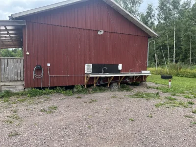 Enkel servicestation med diskho och eluttag vid röd träbyggnad på ställplatsen i Örserum