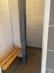 Enkelt men funktionellt duschrum med träbänk och gardindraperier på First Camp Vadstena