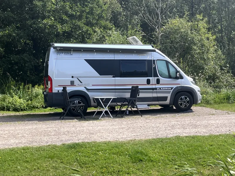 Vi njuter av en skön ställplats omgiven av grönska med utemöblerna redo